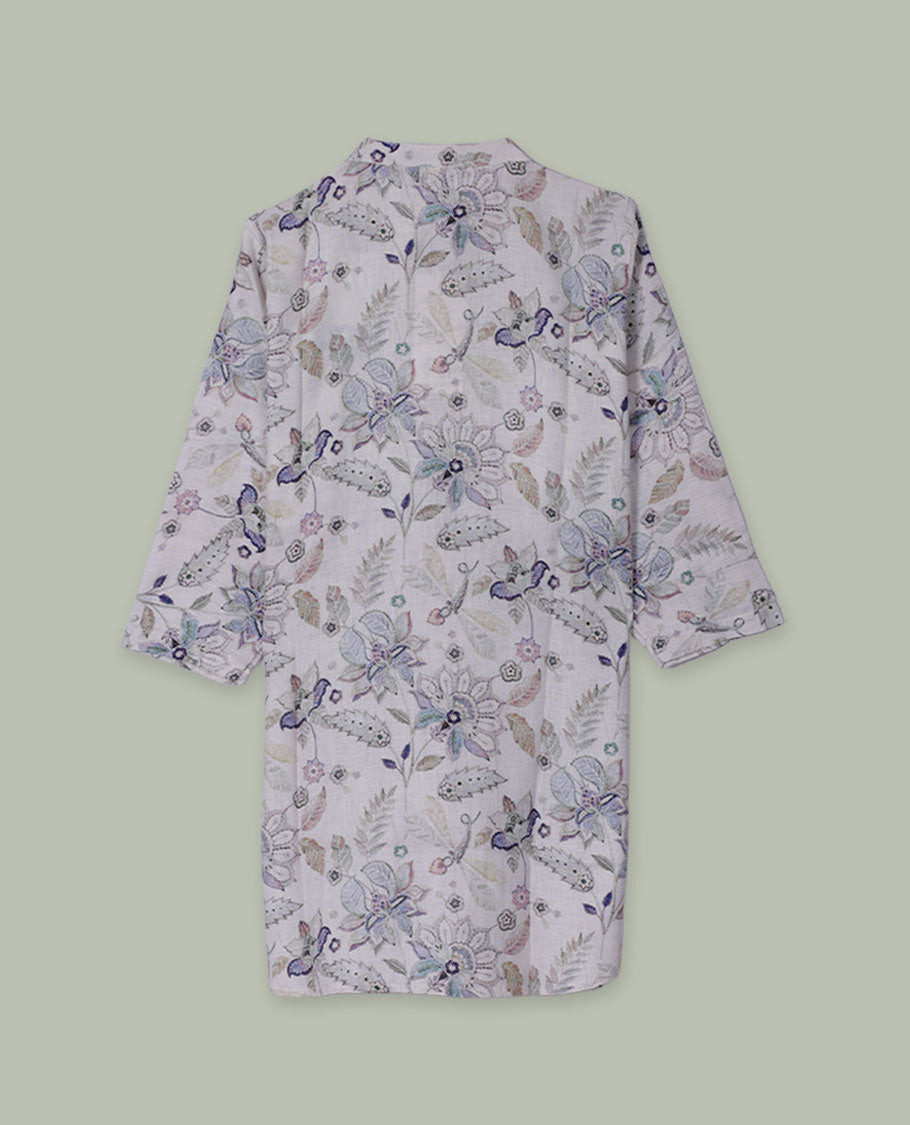 White tunic top with pastel floral and paisley print, band collar, pintuck-detailed front with half button placket, and three-quarter sleeves.