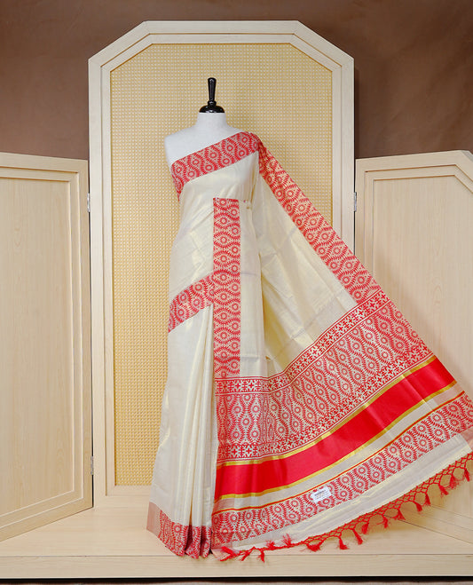 Cream Colour Tissue Kerala Saree Featuring a Plain Body, Enhanced with Red Block  Printed Borders, a Red and Gold Zari Pallu, Red Tassels, and a Matching Blouse Piece.