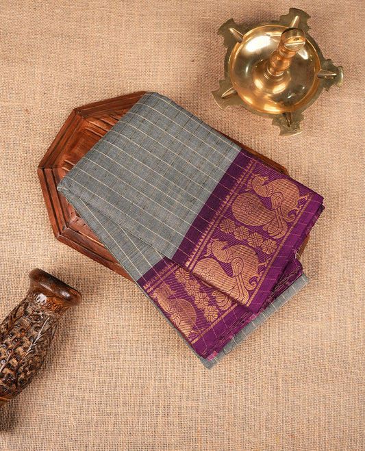 Grey colour sungudi cotton saree featuring gold zari check pattern across body, contrast Purple colour with gold zari peacock pattern on border, without blouse piece.