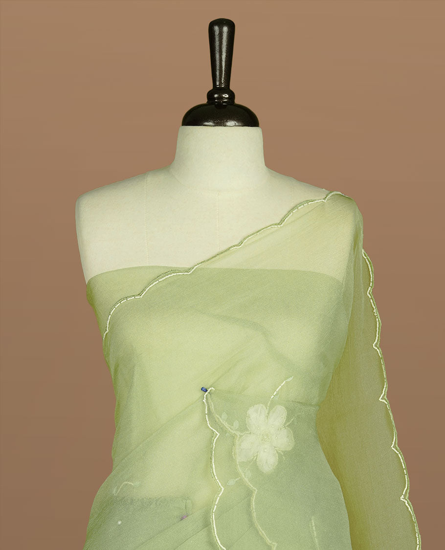 Pastel olive colour crush organza saree featuring white floral work with beats & sequins, highlighting scalp with beats worked border, paired with matching blouse piece.