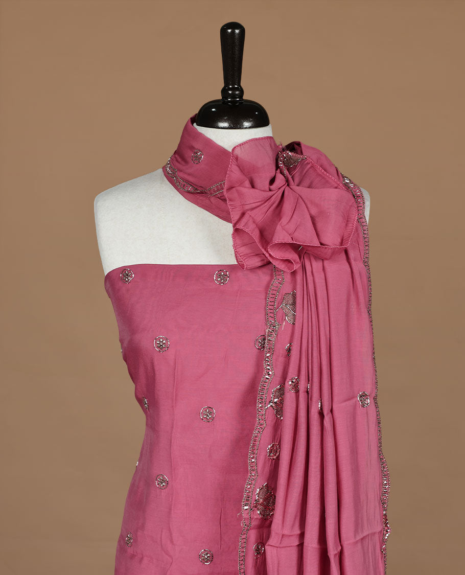 Peachy pink colour churidar material featuring floral cut beats and thread work on body, paired with matching bottom and dupatta.