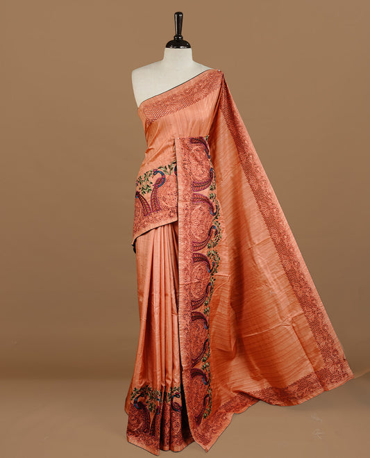 Peach colour Semi Tussar silk saree features an intricate cutwork embroidered peacock motifs on border, paired with a matching unstitched blouse piece.