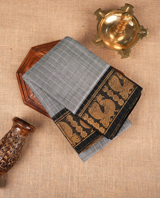 Grey colour sungudi cotton saree featuring gold zari check pattern across body, contrast Black colour with gold zari peacock and floral pattern on border, without blouse piece.