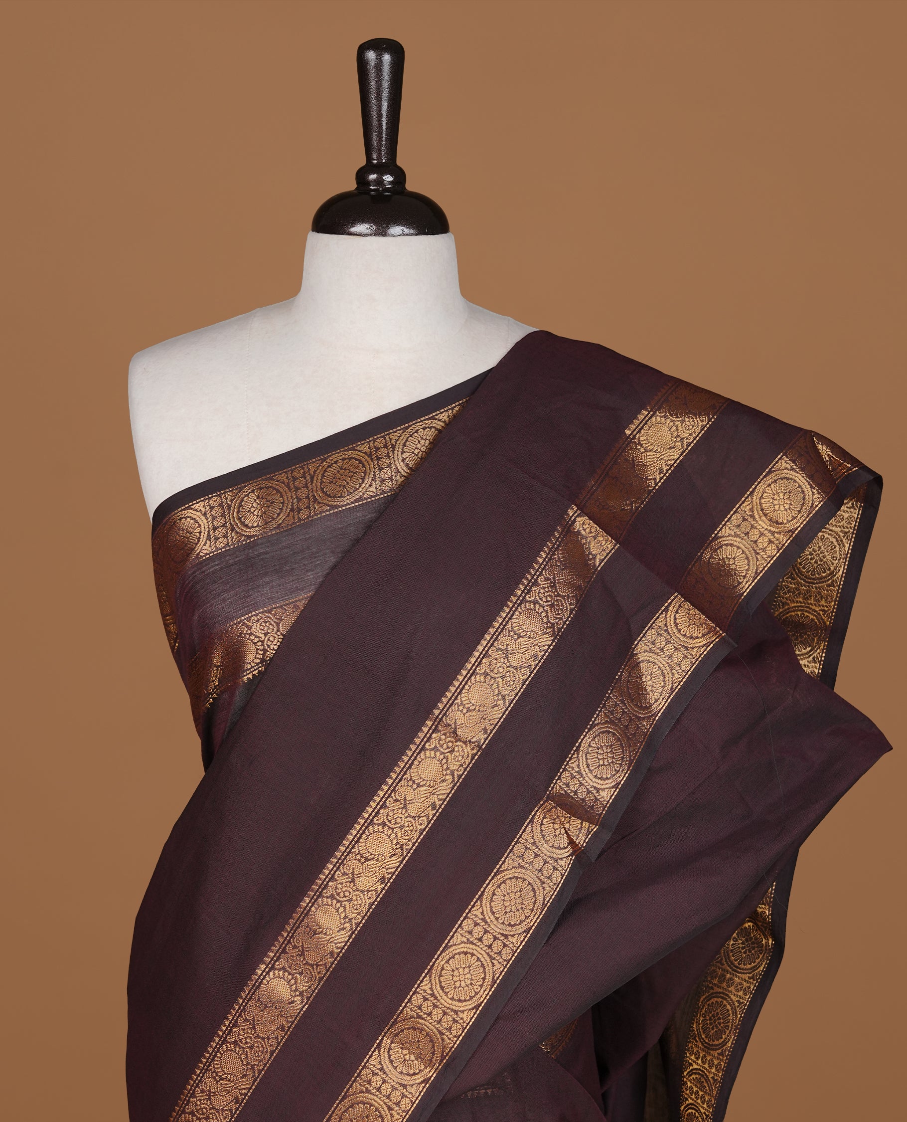 Dark chocolate colour Chettinad cotton saree featuring Elegant plain body, complemented by self colour with gold zari border, paired with matching blouse piece.
