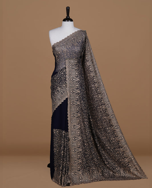 Dark blue colour georgette designer saree featuring Gold thread floral pattern on body highlighting with stone and scalp border, paired with matching blouse piece.