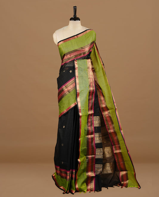 Black colour chettinad cotton saree featuring gold zari motifs on body, complemented by magenta & green colour with zari border, paired with matching blouse piece.