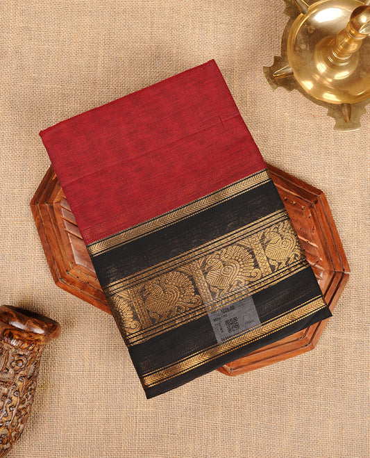 Maroon colour chettinad cotton saree featuring plain body, contrast black colour with traditional gold zari border paired with matching blouse.