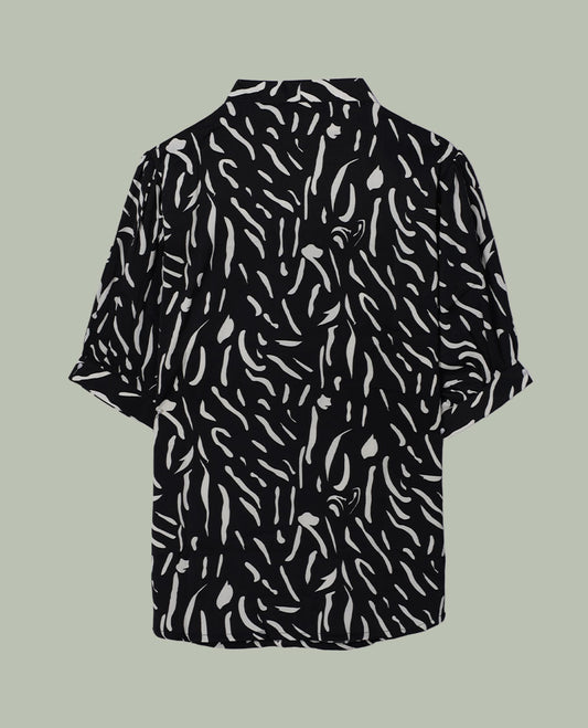 Black short-sleeve shirt top with collared neckline and all-over white abstract dash print, shown from the back.