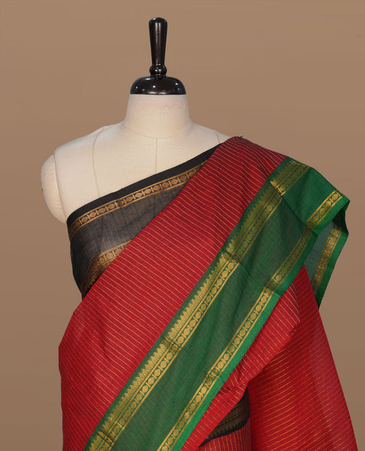 Maroon colour chettinad cotton featuring gold zari check pattern on body , complemented by contrast Green colour with gold zari border, paired with matching blouse piece.
