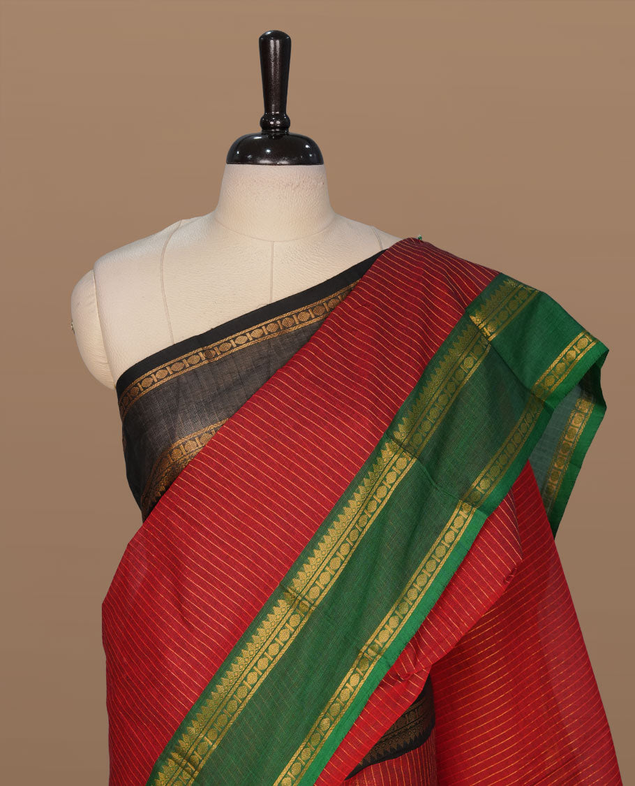 Maroon colour chettinad cotton featuring gold zari check pattern on body , complemented by contrast Green colour with gold zari border, paired with matching blouse piece.