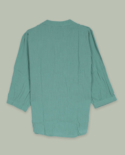 Sea green three-quarter sleeve tunic top with rounded band neckline, front floral embroidered yoke, fabric-covered button placket, and soft pleating below the yoke.