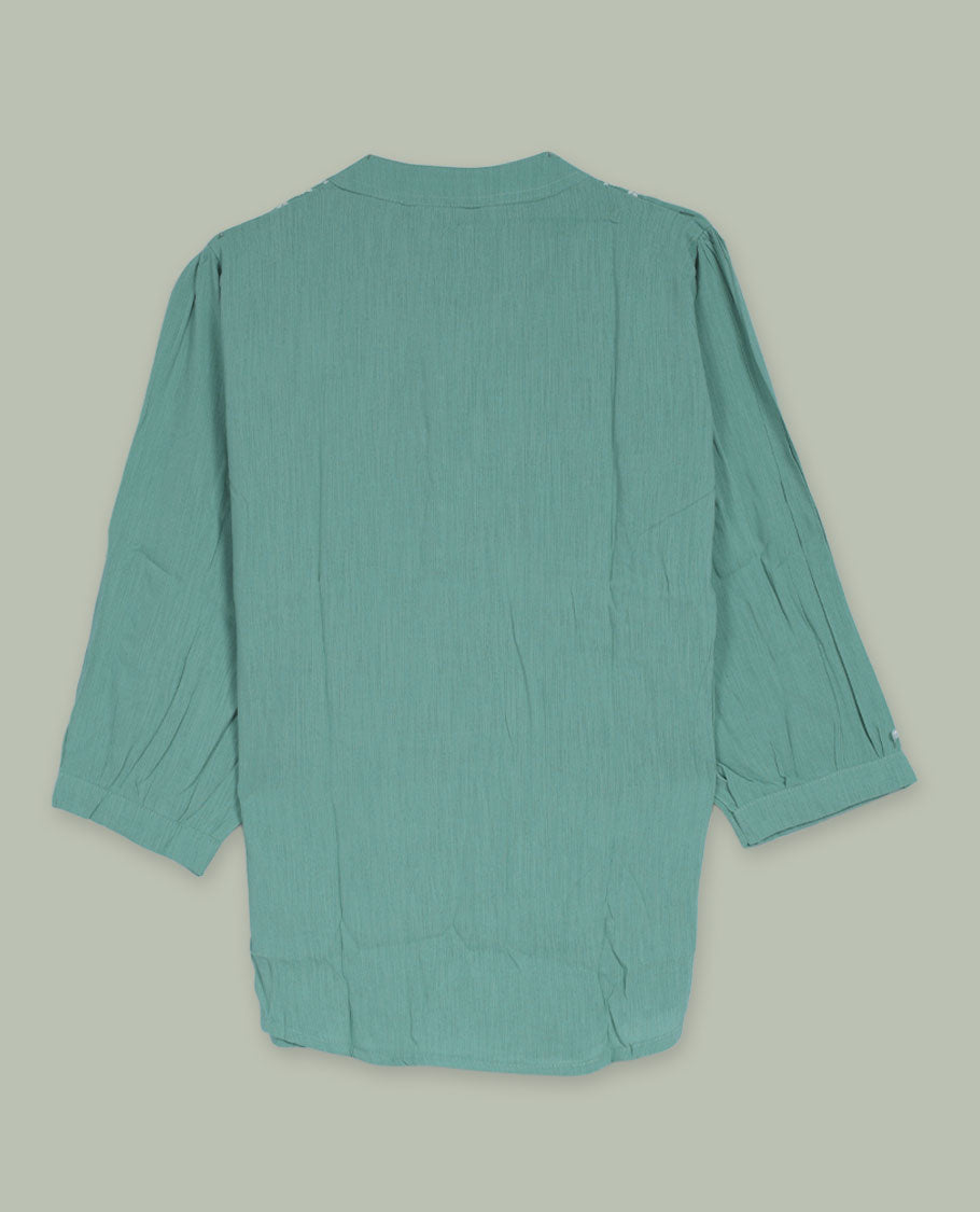 Sea green three-quarter sleeve tunic top with rounded band neckline, front floral embroidered yoke, fabric-covered button placket, and soft pleating below the yoke.