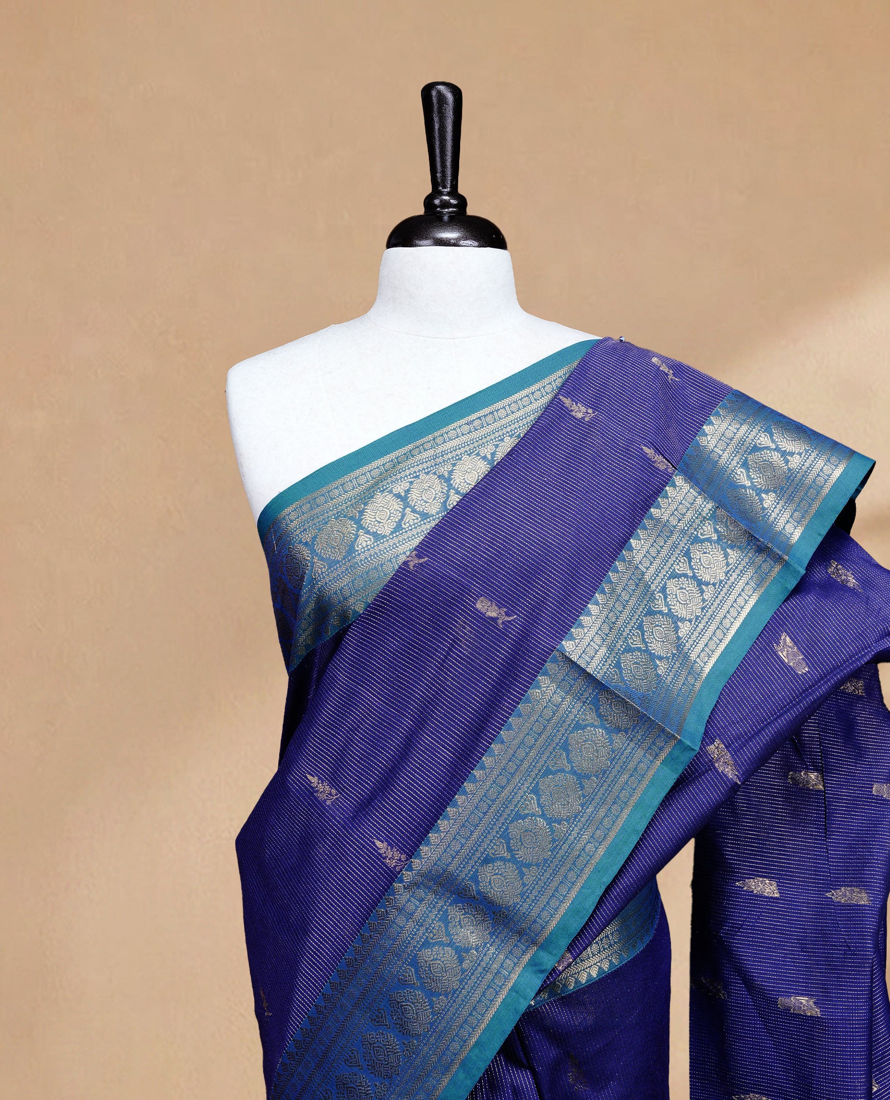 Navy blue colour chettinad cotton saree featuring gold zari stripes & motifs on body, complemented by Contrast Teal colour with zari border, paired with matching blouse piece.