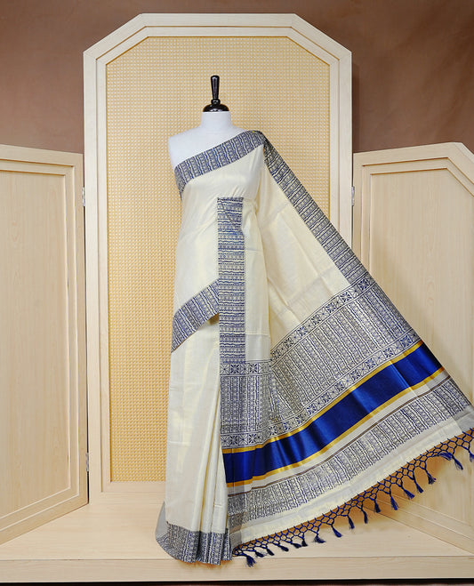 Cream Colour Tissue Kerala Saree Featuring Blue Geometric Digital Prints Along the Border, Enhanced with a Royal Blue and Gold Zari Border, Traditional Printed Pallu, Finished with Blue Tassels and a Matching Blouse Piece