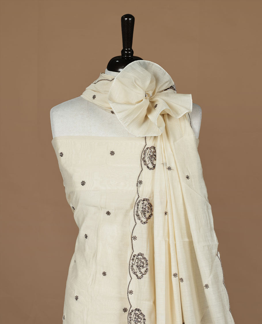 Off white colour churidar material featuring floral cut beats and thread work on body, paired with matching bottom and dupatta.