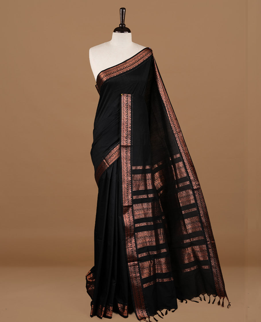 Black colour kalyani cotton saree featuring gold zari motifs on body, highlighting self colour with Antique gold zari border, paired with matching blouse piece.
