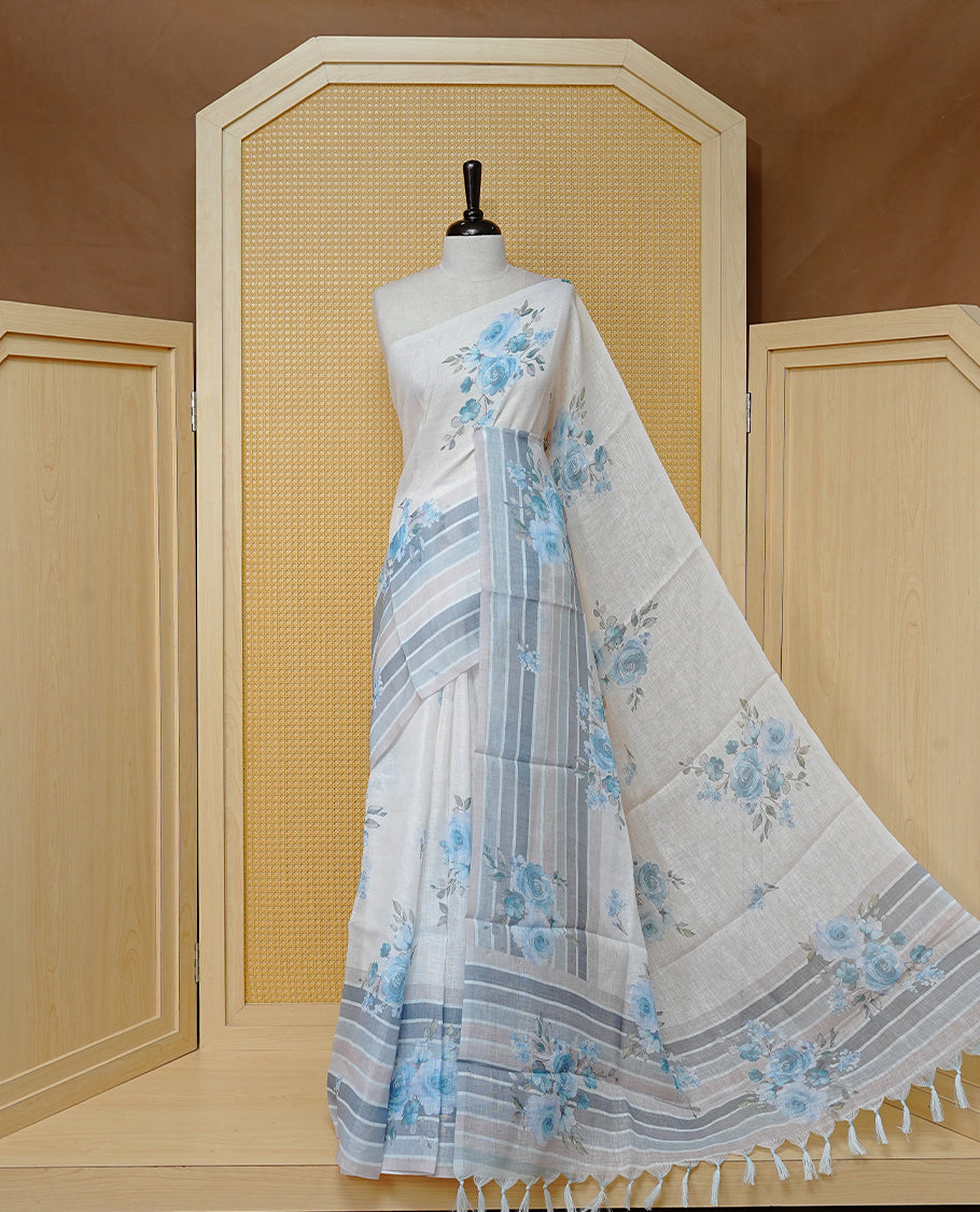 Cream colour semi linen saree featuring Blue colour floral print on body, complemented by contrast Strip pattern border, comes with matching blouse piece.