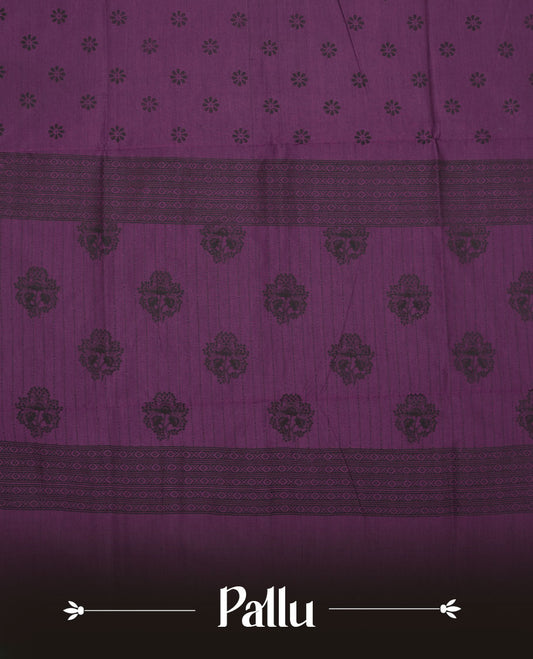 Grape Purple colour poly cotton saree with black floral butti motifs on the body, paired with a matching pallu featuring black ornate floral jaal and stripes on the border, and a coordinated all‑over black paisley printed blouse piece.