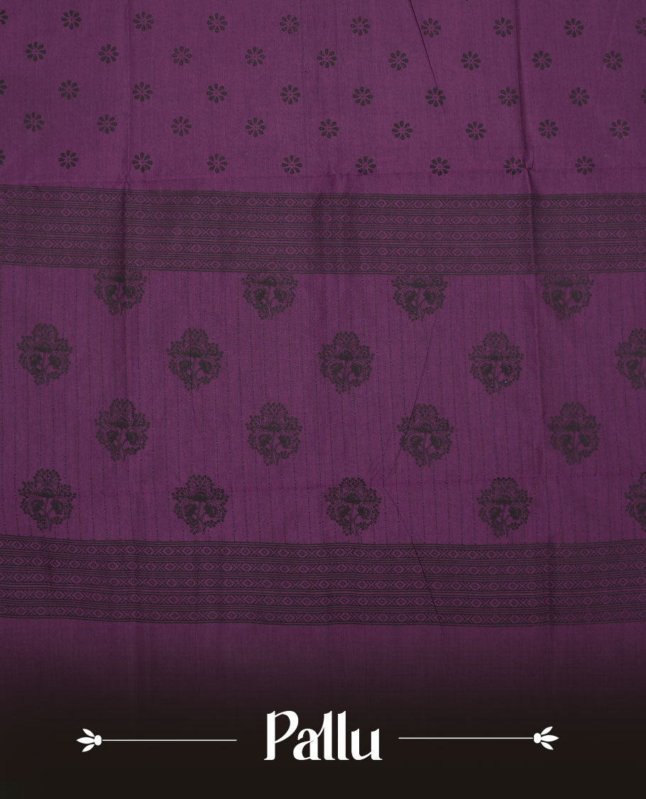 Grape Purple colour poly cotton saree with black floral butti motifs on the body, paired with a matching pallu featuring black ornate floral jaal and stripes on the border, and a coordinated all‑over black paisley printed blouse piece.