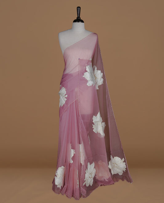 Pastel Mauve colour semi organza saree featuring white floral & gold thread pattern, highlighting scalp design border, paired with matching blouse piece.
