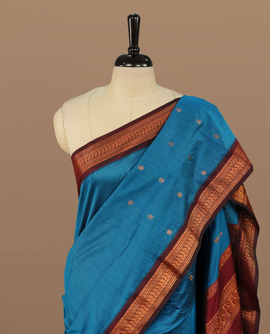 Blue colour kalyani cotton saree featuring antique zari motifs on body, complemented by Maroon colour with Antique zari border, paired with matching blouse piece.