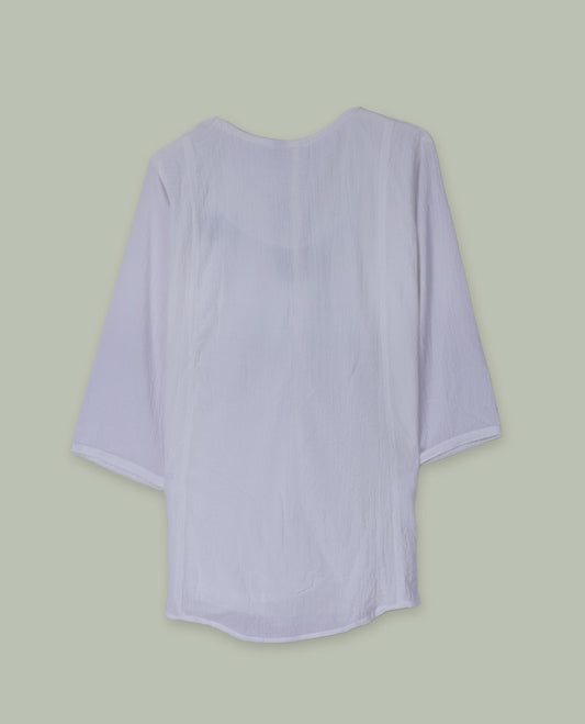 White three-quarter sleeve tunic top with round neckline, front yoke featuring blue and green floral embroidery, and tie-up detail at the neck.