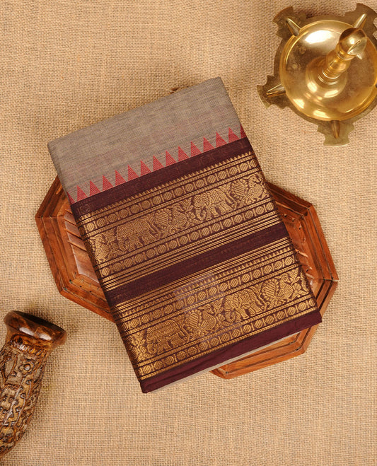 Grey colour chettinad cotton saree featuring plain body, paired with a black colour traditional gold zari border paired with matching blouse.