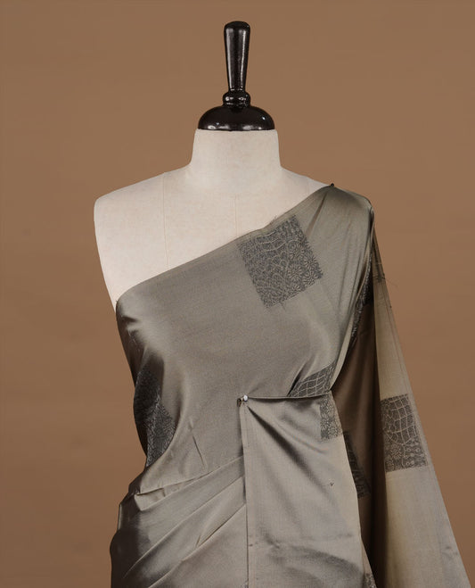 Greyish green soft silk saree features a sleek borderless design with intricate antique zari motifs, flowing into a seamless self colored pallu and a matching blouse piece.