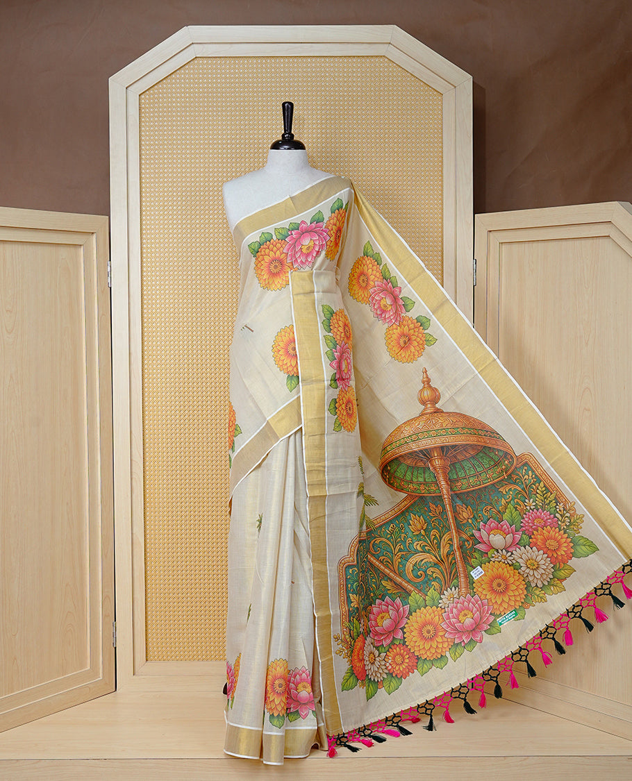 Cream Colour Tissue Kerala Saree Featuring Vibrant Digital Floral Prints & Onam Team Printed Pallu, Beautifully Enhanced With A Classic Gold Zari Border And Contrast Tassels. Paired With A Matching Blouse Piece.