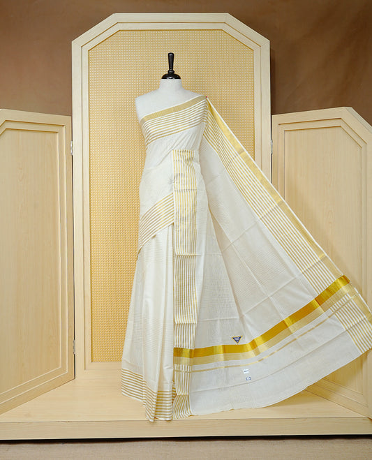 Cream Colur Cotton Kerala Saree Featuring Gold Zari Strips Across On The Body, Classic  Gold Zari Border & Pallu,Paired With A Matchinf Blouse Piece.
