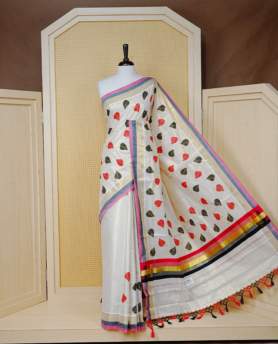 Cream Colour Tissue  Kerala Saree Featuring Red and Black Leaf Prints Across the Body, Enhanced with a Gold Zari, Red and Black Border &  Pallu, Red and Black Tassels, and a Matching Blouse Piece.