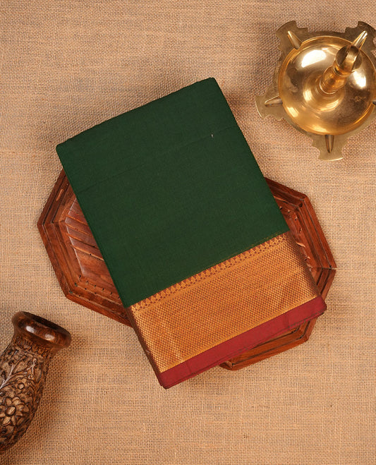 Dark green colour chettinad cotton saree featuring elegant plain body highlighting contrast maroon colour colour with gold zari traditional border, pallu and paired with matching blouse piece.