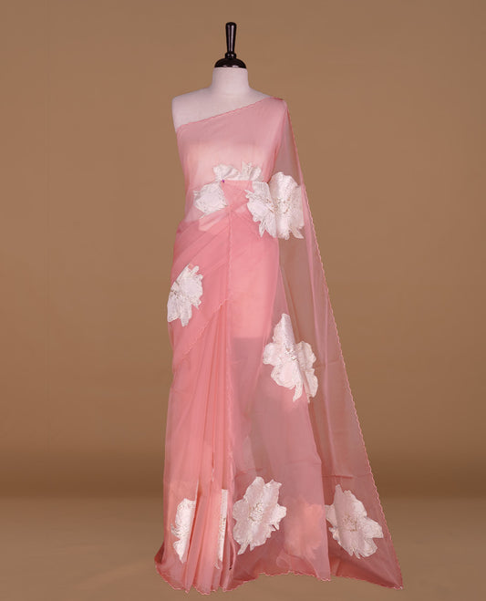 Pastel pink colour semi organza saree featuring white floral & gold thread pattern, highlighting scalp design border, paired with matching blouse piece.