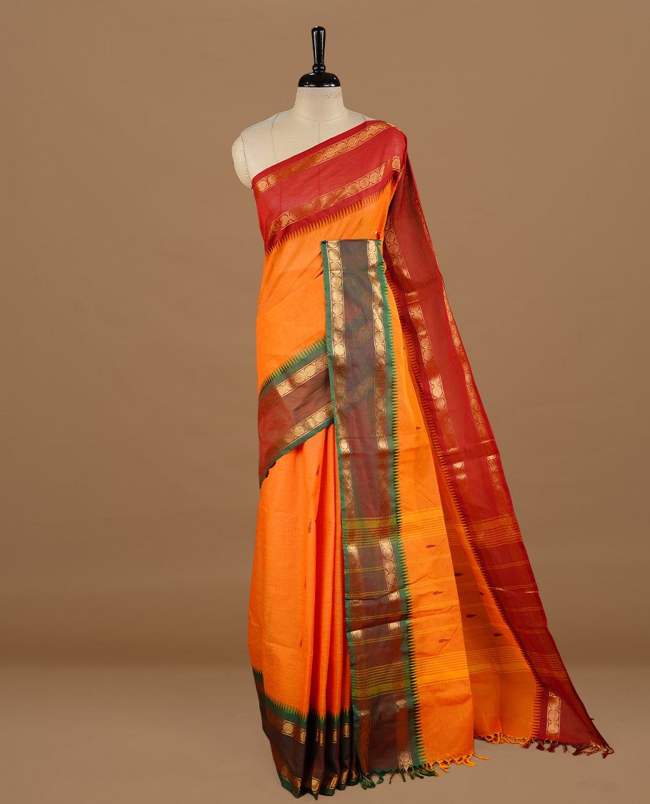 Orange colour chettinad cotton saree featuring motifs on body, complemented by Green colour with zari border, paired with matching blouse piece.