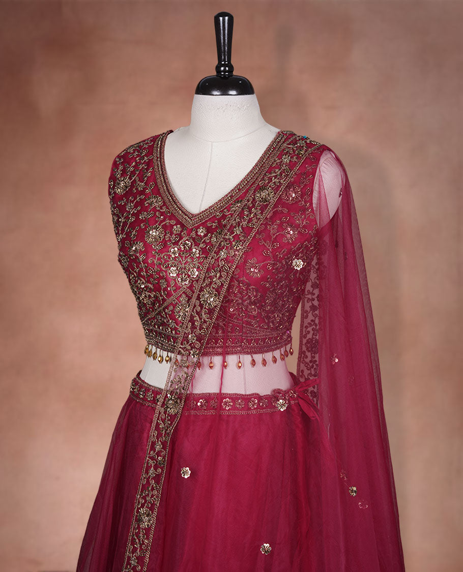 Maroon colour lehenga set with stitched sleeveless Antique thread embroidered & beats worked  blouse featuring sheer neckline, matching stitched flared lehenga, and plain sheer dupatta.