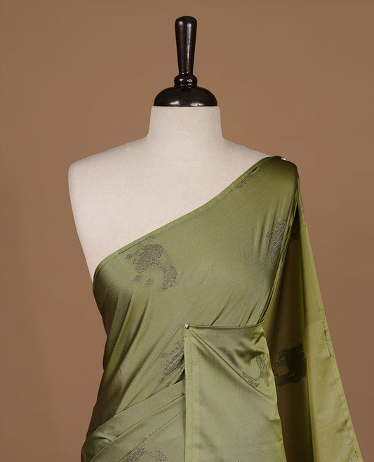 Olive colour soft silk saree features a sleek borderless design with intricate antique zari motifs, flowing into a striking contrast green pallu and a matching blouse piece.