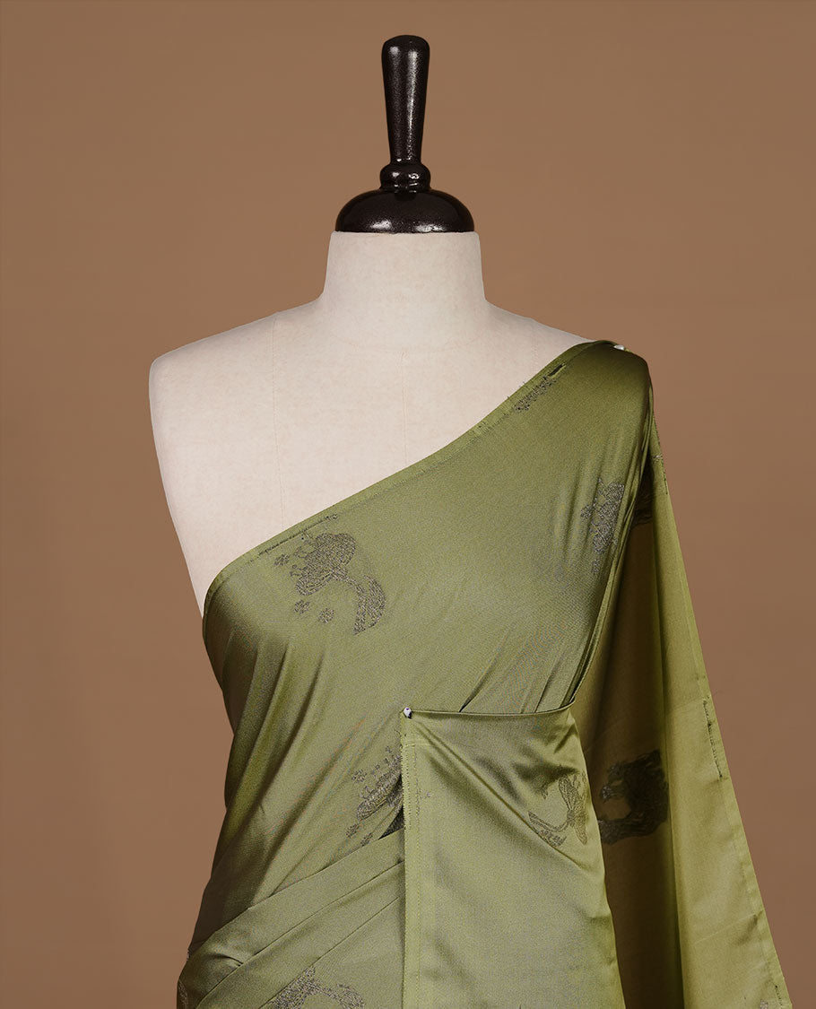 Olive colour soft silk saree features a sleek borderless design with intricate antique zari motifs, flowing into a striking contrast green pallu and a matching blouse piece.