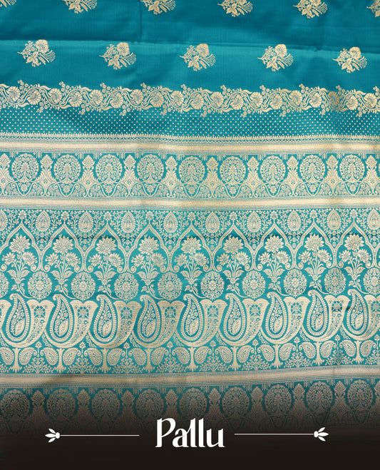 Teal blue colour Banaras Satin Crepe saree featuring gold zari floral motifs on the body, a richly woven traditional border with intricate gold zari detailing, and paired with a matching blouse.