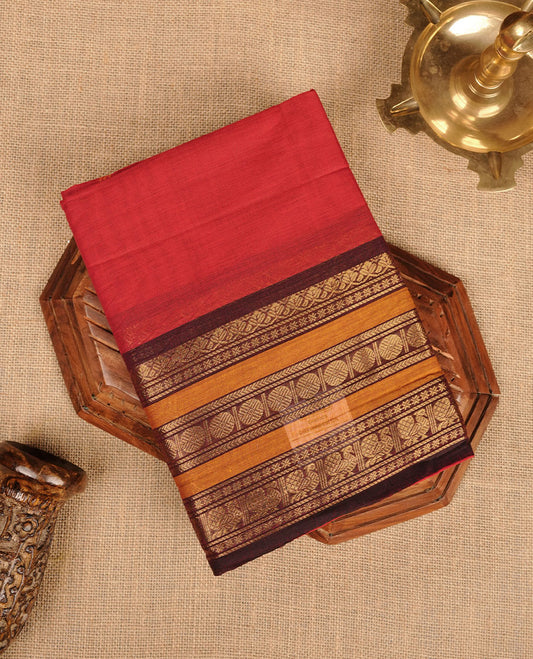 Red colour chettinad cotton saree featuring plain body, contrast chocolate brown and mustard colour with traditional gold zari border paired with matching blouse.