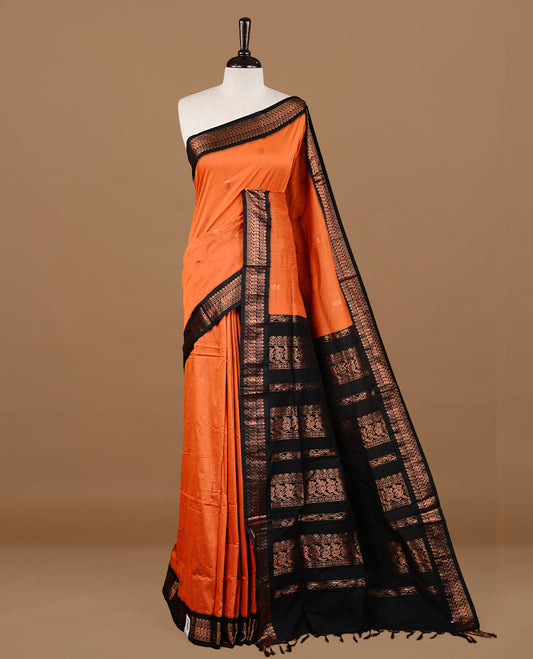 Orange colour kalyani cotton saree featuring gold zari motifs on body, highlighting contrast Black colour with Antique gold zari border, paired with matching blouse piece.