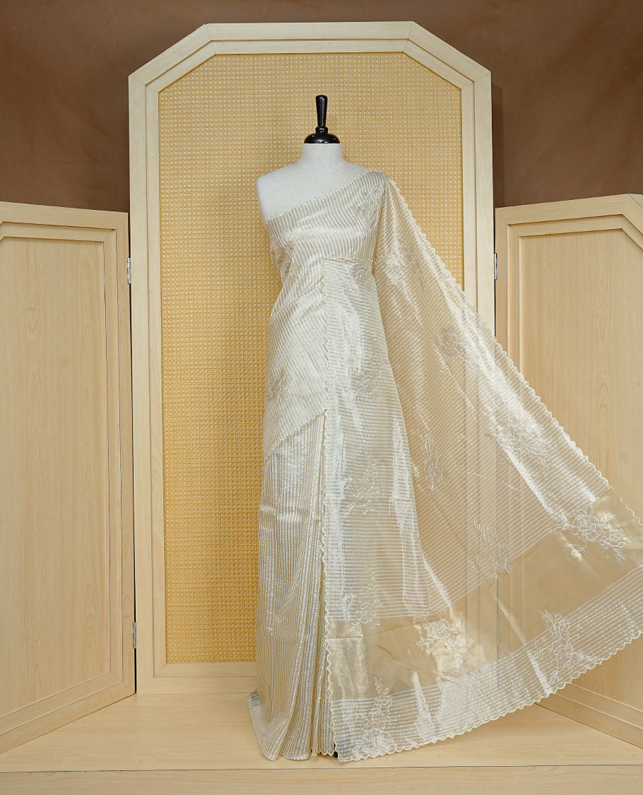 Cream colour Organza Saree featuring floral thread Work & Gold zari strip Design on body, Scallop border, comes with matching blouse piece.