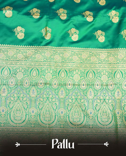 Emerald green colour Banaras Satin Crepe saree featuring gold zari floral motifs on the body, a richly woven traditional border with intricate gold zari detailing, and paired with a matching blouse.