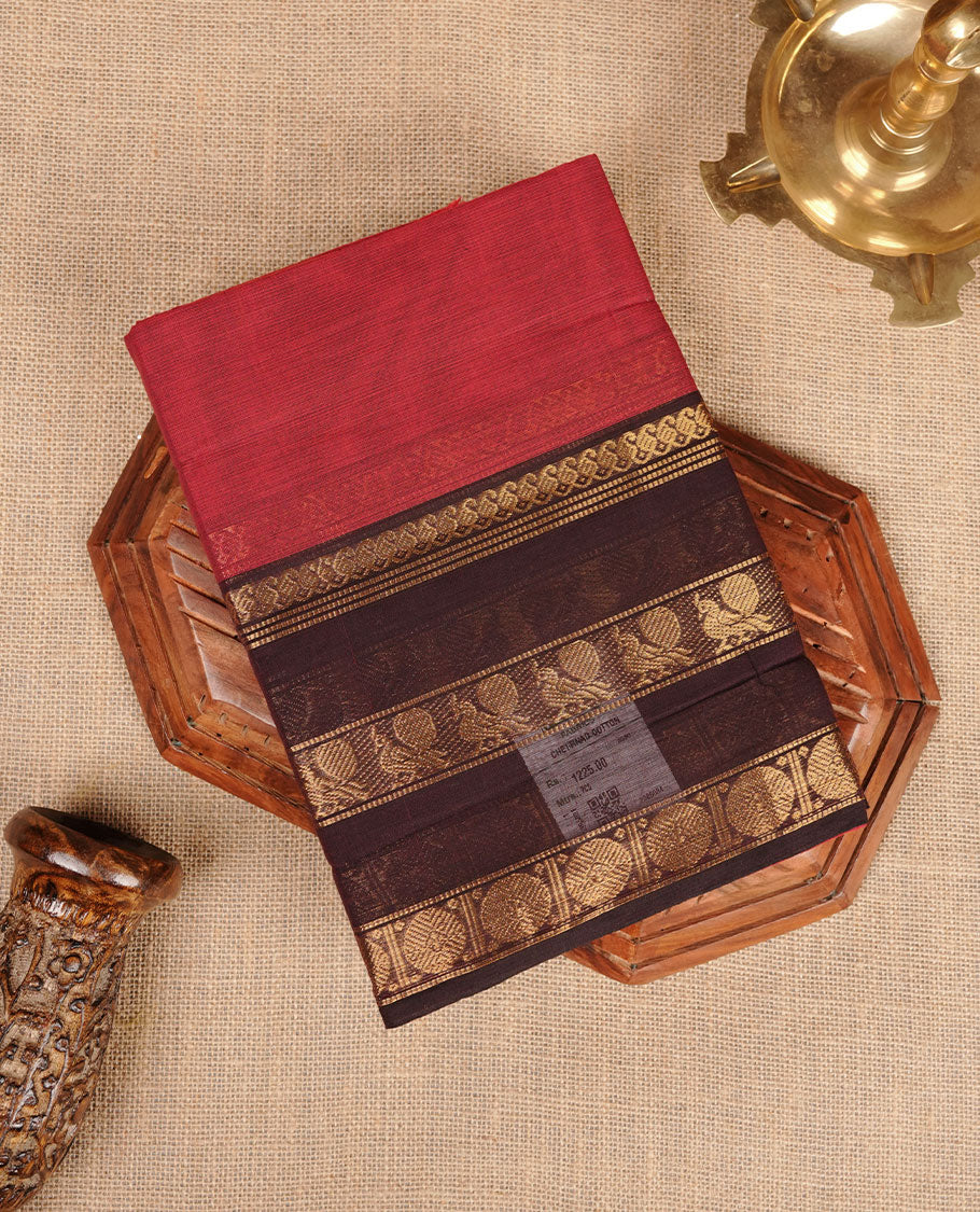 Red colour chettinad cotton saree featuring plain body, contrast chocolate brown colour with traditional gold zari border paired with matching blouse.