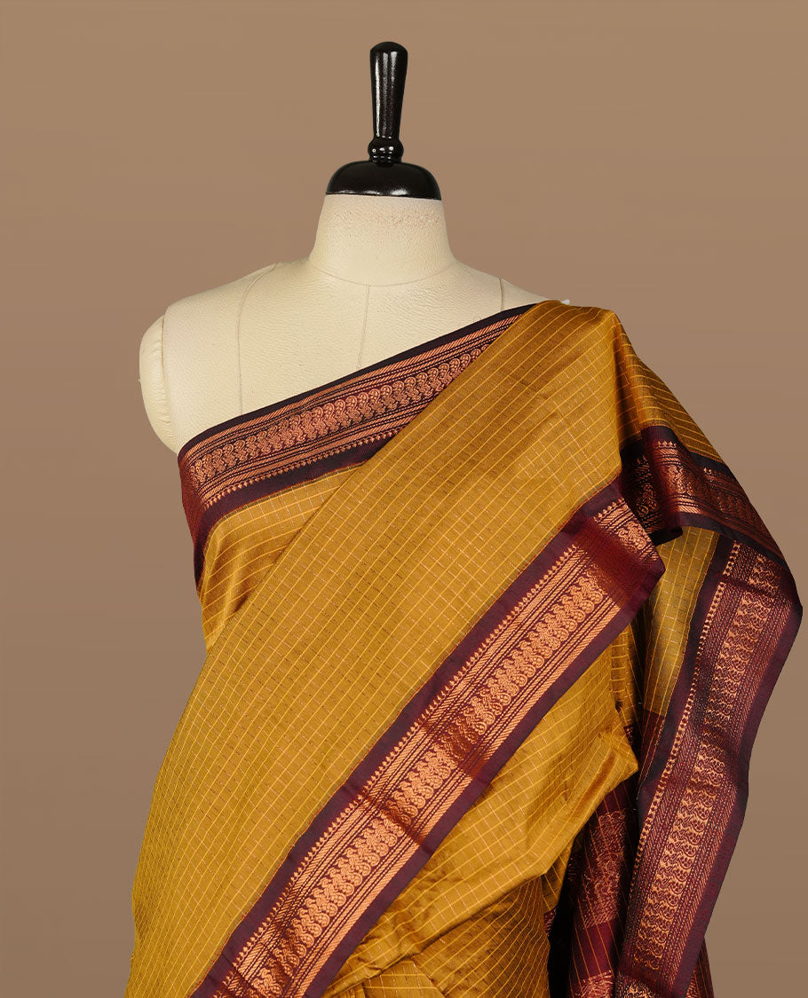 Mustard colour kalyani cotton saree featuring gold zari check pattern on body, complemented by Maroon colour with Antique zari border, paired with matching blouse piece.
