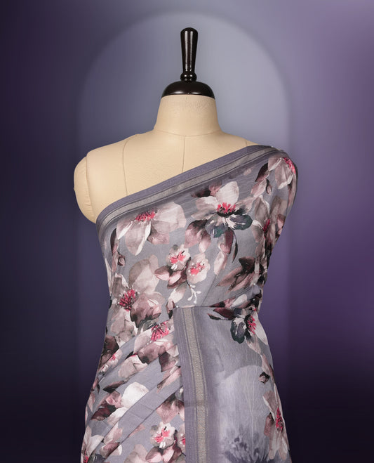 Grey colour  saree adorned with elegant floral prints on the body, enhanced with a subtle matching border, complemented by a beautifully printed pallu featuring blooming flowers, and paired with a matching blouse.