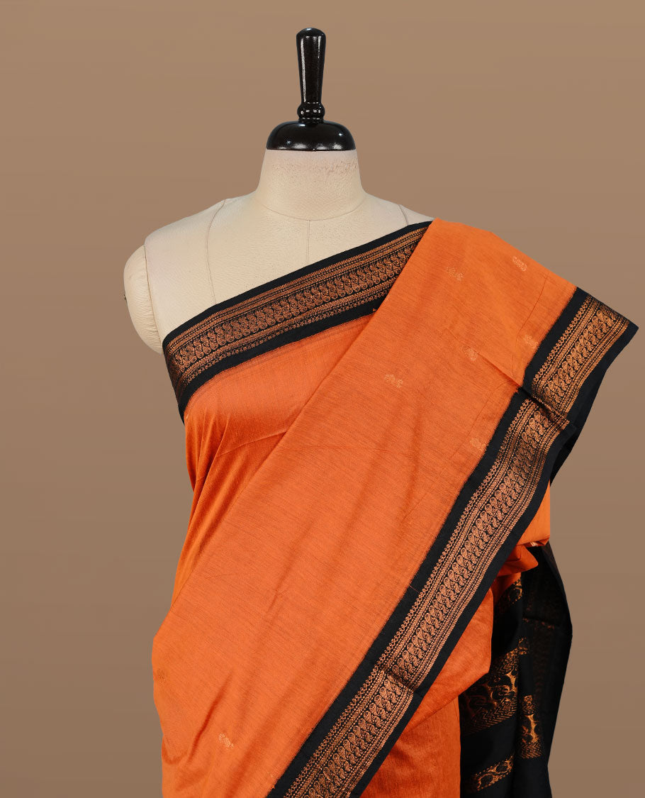 Orange colour kalyani cotton saree featuring antique zari motifs on body, complemented by black colour with Antique zari border, paired with matching blouse piece.