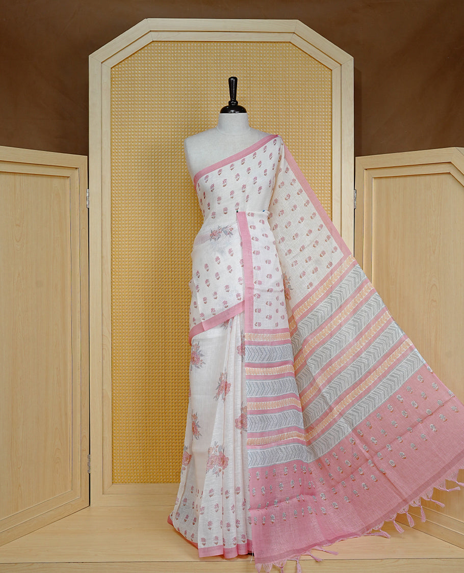 Cream colour semi linen saree featuring Floral printed buttas on body, complemented by contrast Peach colour border, comes with matching blouse piece.