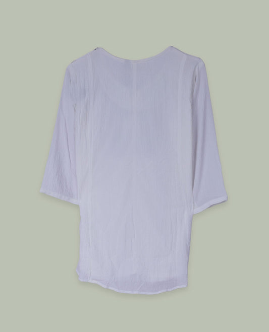 White three-quarter sleeve tunic top with round neckline and front yoke featuring red and green floral embroidery with tie-up detail at the neck.