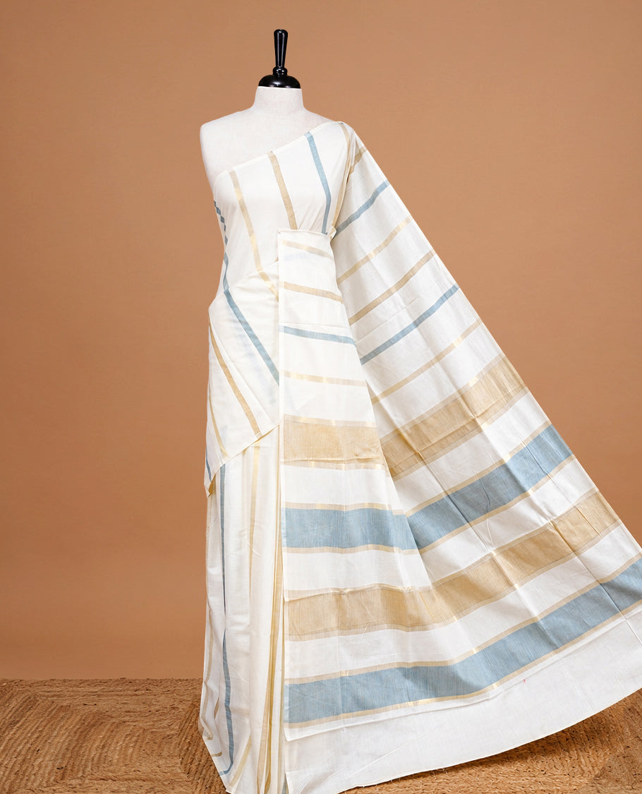 Cream Colour Cotton Kerala Saree Featuring Light Grey & Gold Zari Strips On The Body & Pallu, Paired With A Matching Blouse Piece.