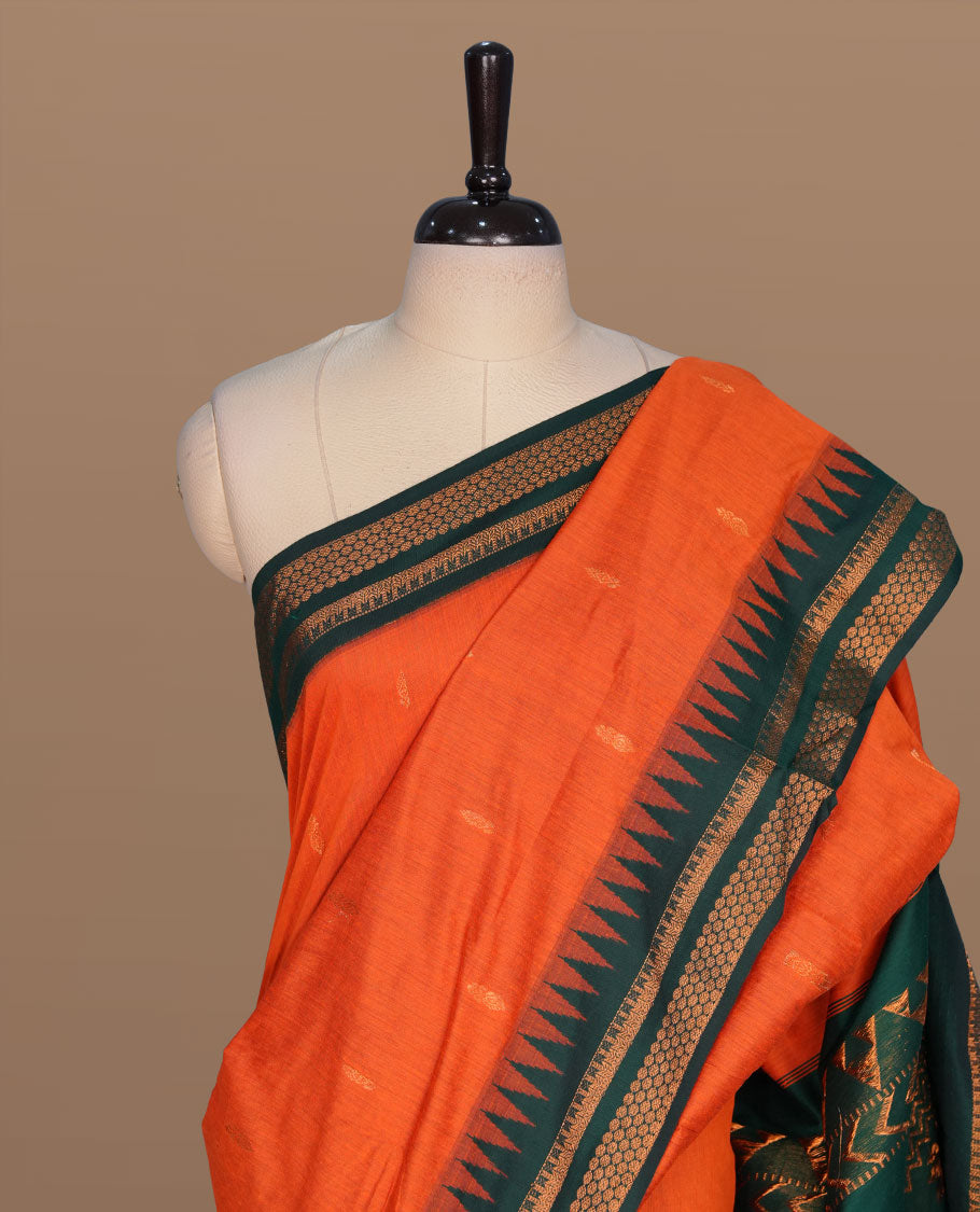 Orange colour kalyani cotton saree featuring gold zari motifs on body, complemented by contrast green color with gold zari pattern border , paired with matching blouse piece.